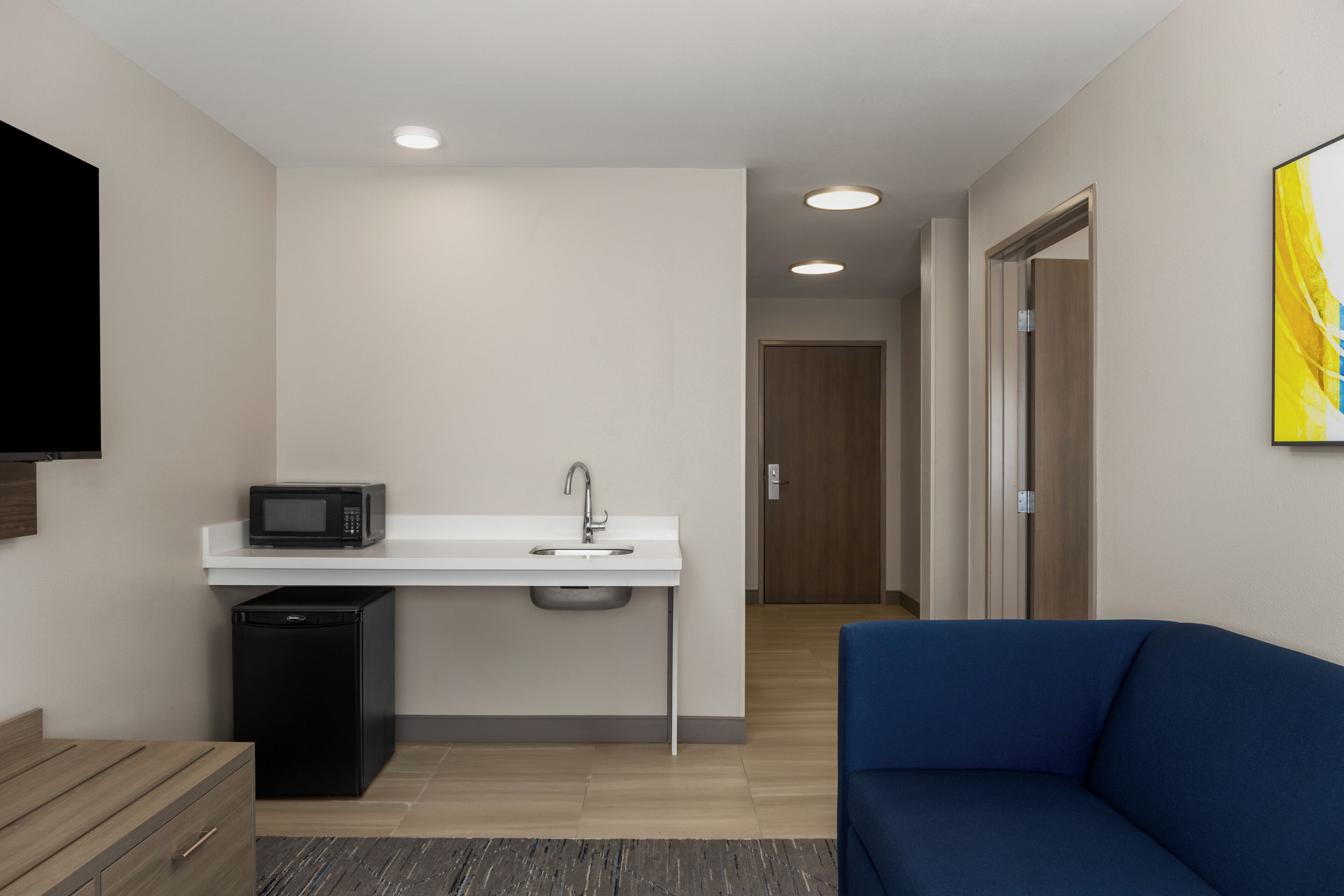 A modern kitchenette with a microwave, sink, and refrigerator.