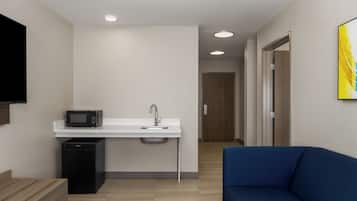 A modern kitchenette with a microwave, sink, and refrigerator.