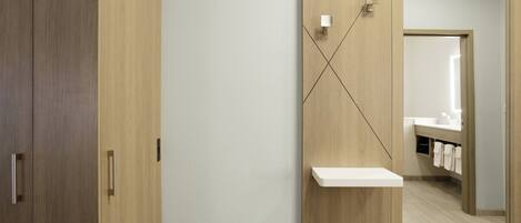 A bathroom with a wooden cabinet, a mirror with a shelf, and a towel rack.