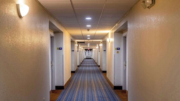 A hotel hallway with a carpeted floor, light fixtures, and doors numbered 207 and 206. - Days Inn & Suites by Wyndham Houston North/Aldine (Houston)