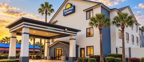 A Days Inn & Suites hotel with a covered entrance, palm trees, and a parking lot with handicapped parking.
