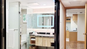 Un baño moderno con cabina de ducha de vidrio, un espejo grande y un lavabo con encimera.