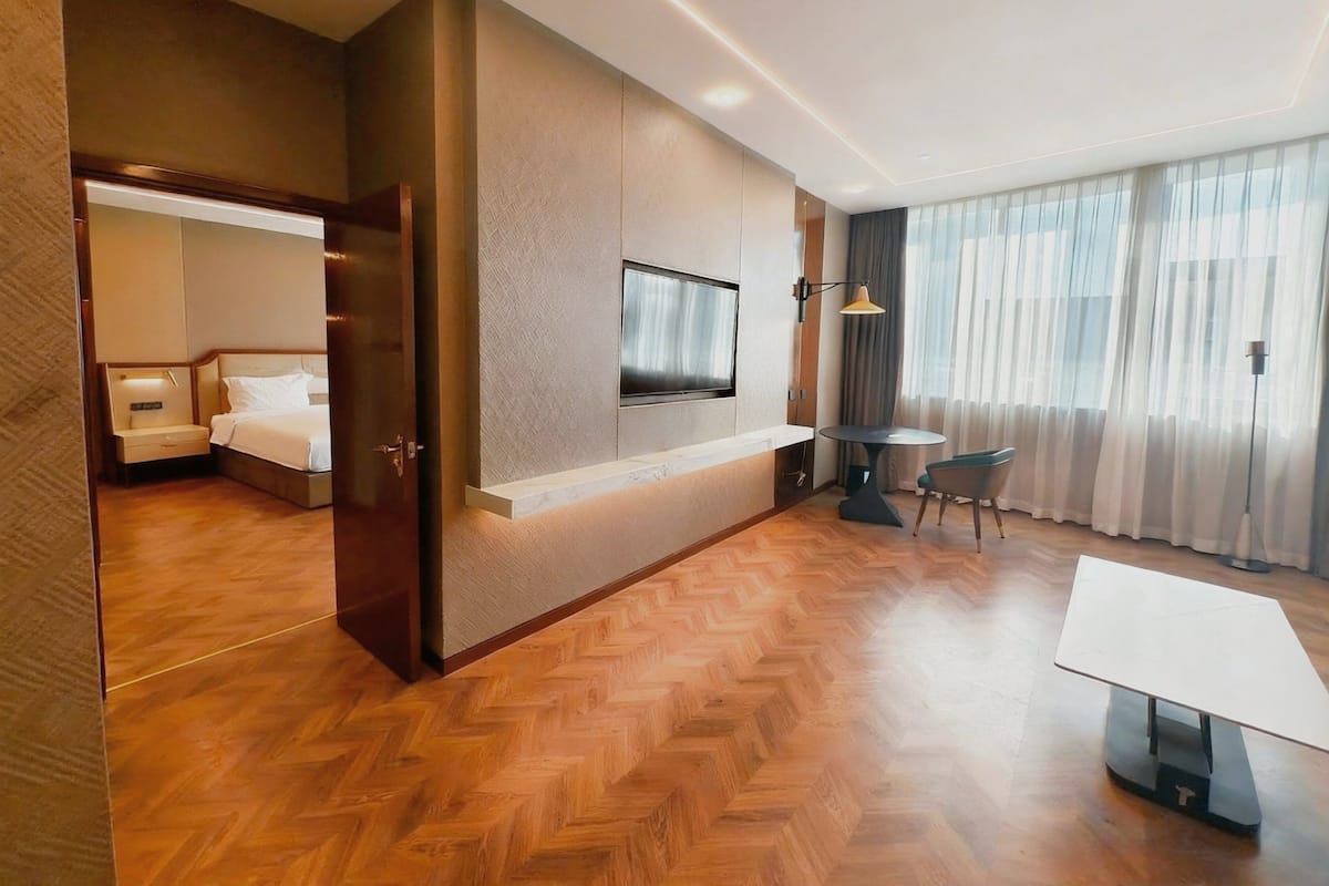A hotel room with a bed, a TV, a desk, and a chair.
