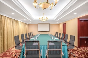 A conference room with a long table, chairs, a projector screen, and a chandelier. - Holiday Inn Beijing Chang An West by IHG (Beijing)