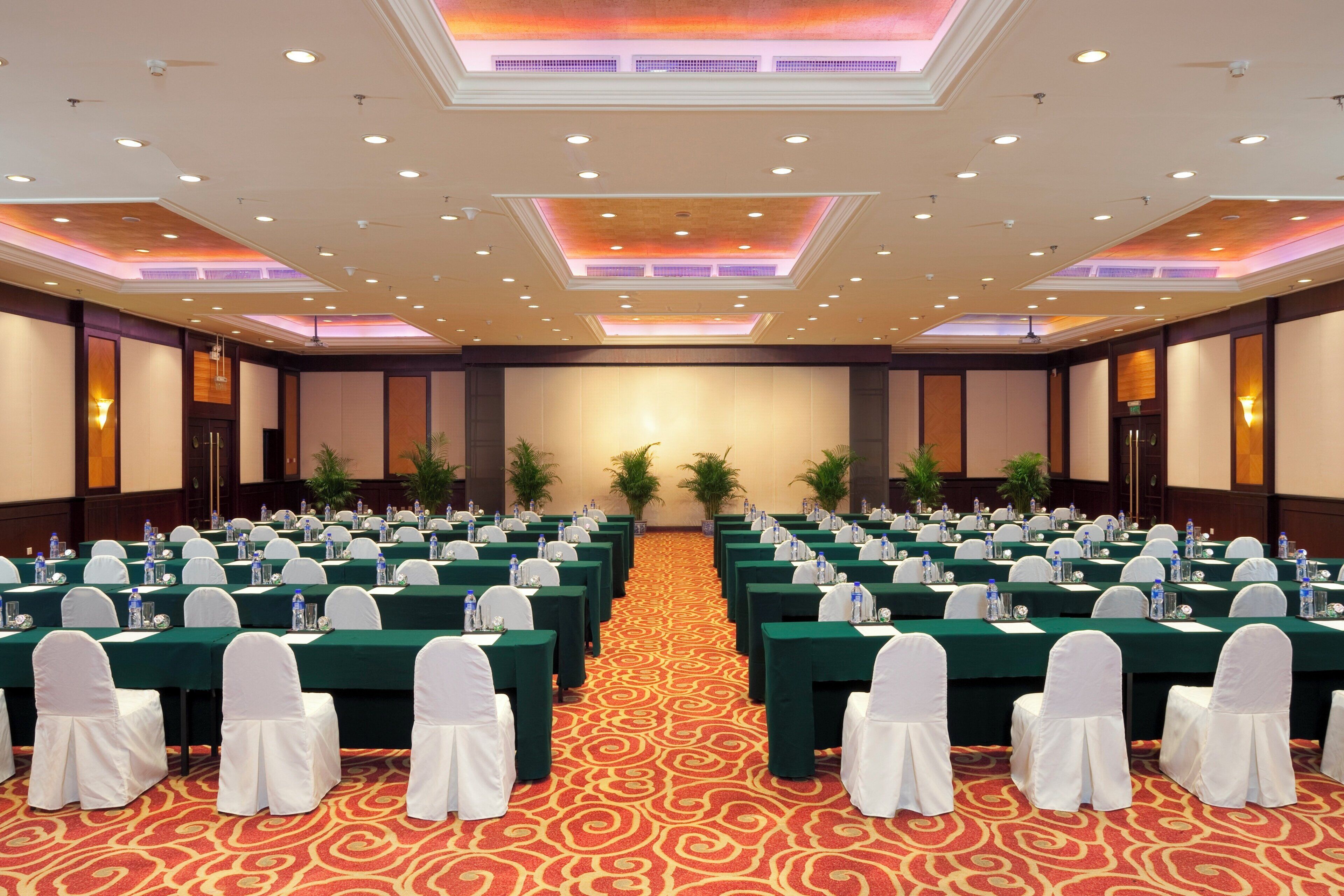 A conference room with rows of tables, white chairs, and water bottles.