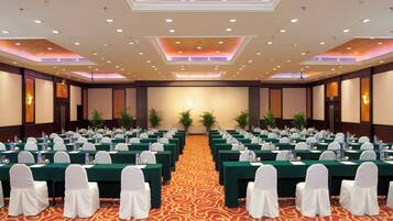 A conference room with rows of tables, white chairs, and water bottles.