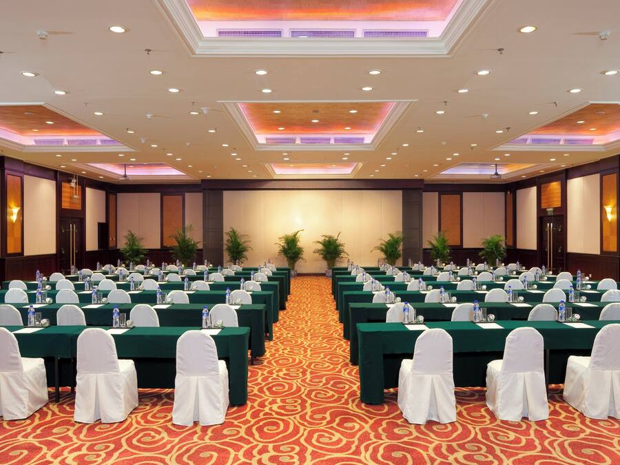 A conference room with rows of tables, white chairs, and water bottles.