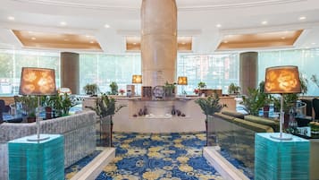 A lobby with a central column, seating areas, and a patterned floor.