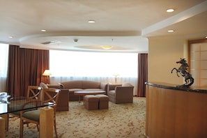 Habitación de hotel con zona de estar que incluye un sofá, sillas y una mesita.