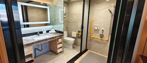 Un baño moderno con tocador de mármol, cabina de ducha de vidrio y retrete.