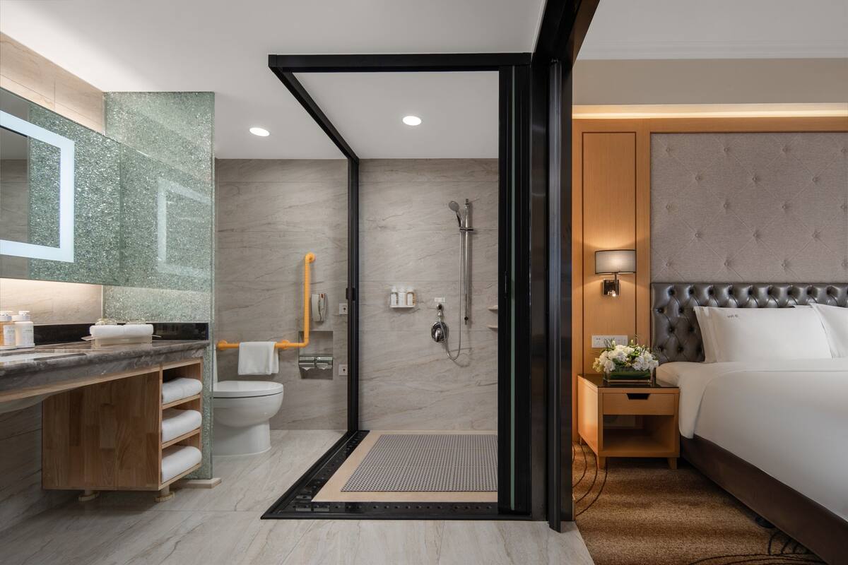 A modern hotel bathroom with a shower, toilet, and sink.
