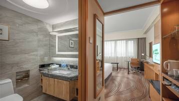 Un baño de hotel con pared de mármol, armarios de madera y un lavamanos.