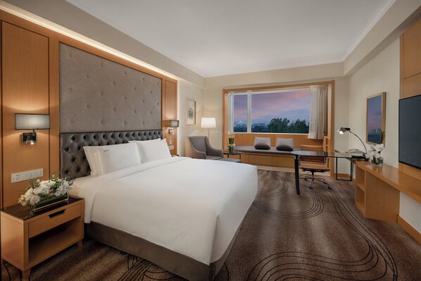 A hotel room with a large bed, a desk, a chair, a TV, and a window with a city view. - Holiday Inn Beijing Chang An West by IHG (Beijing)