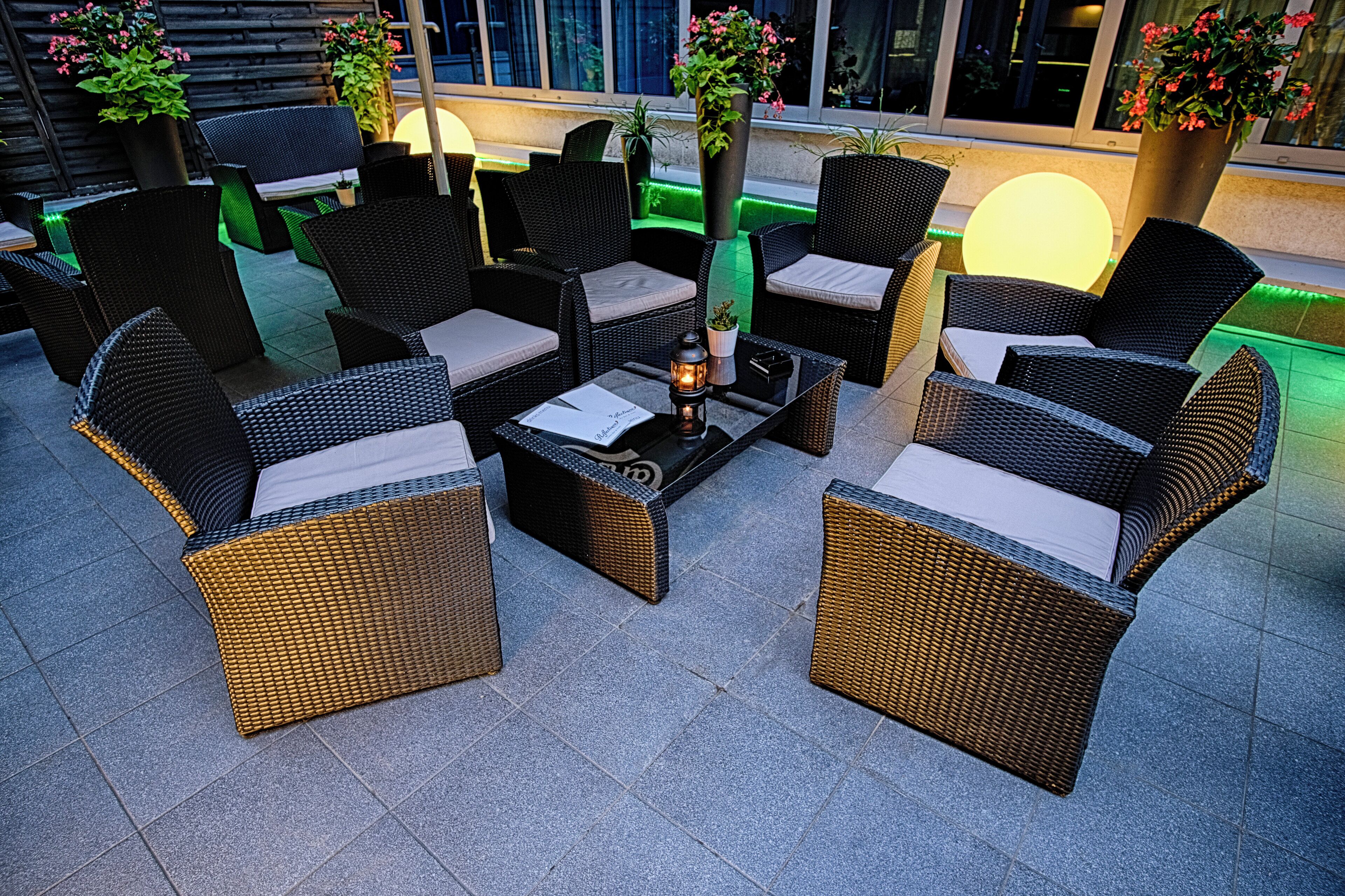 An outdoor seating area with wicker furniture and potted plants.