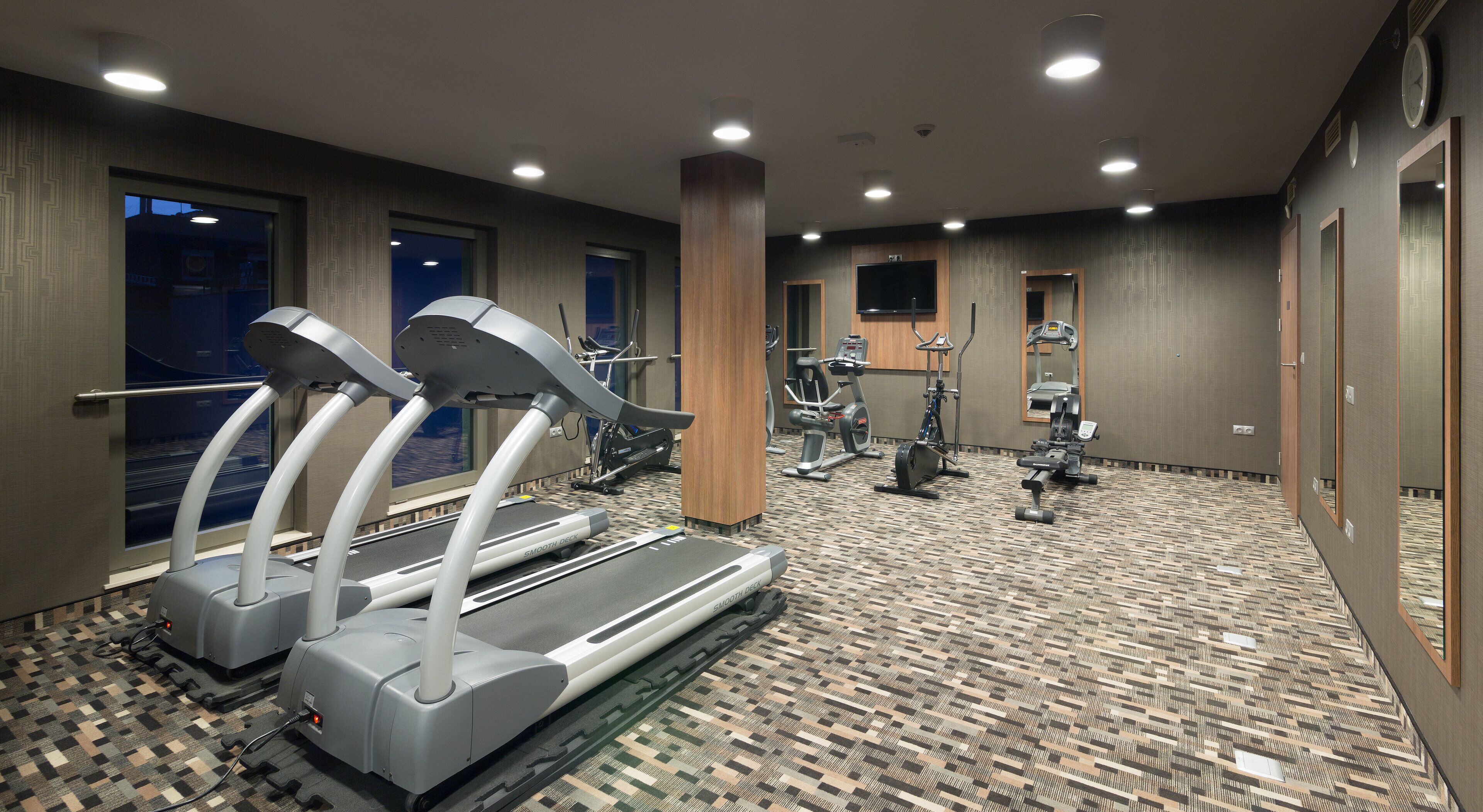 A gym with treadmills, elliptical machines, and weight equipment.