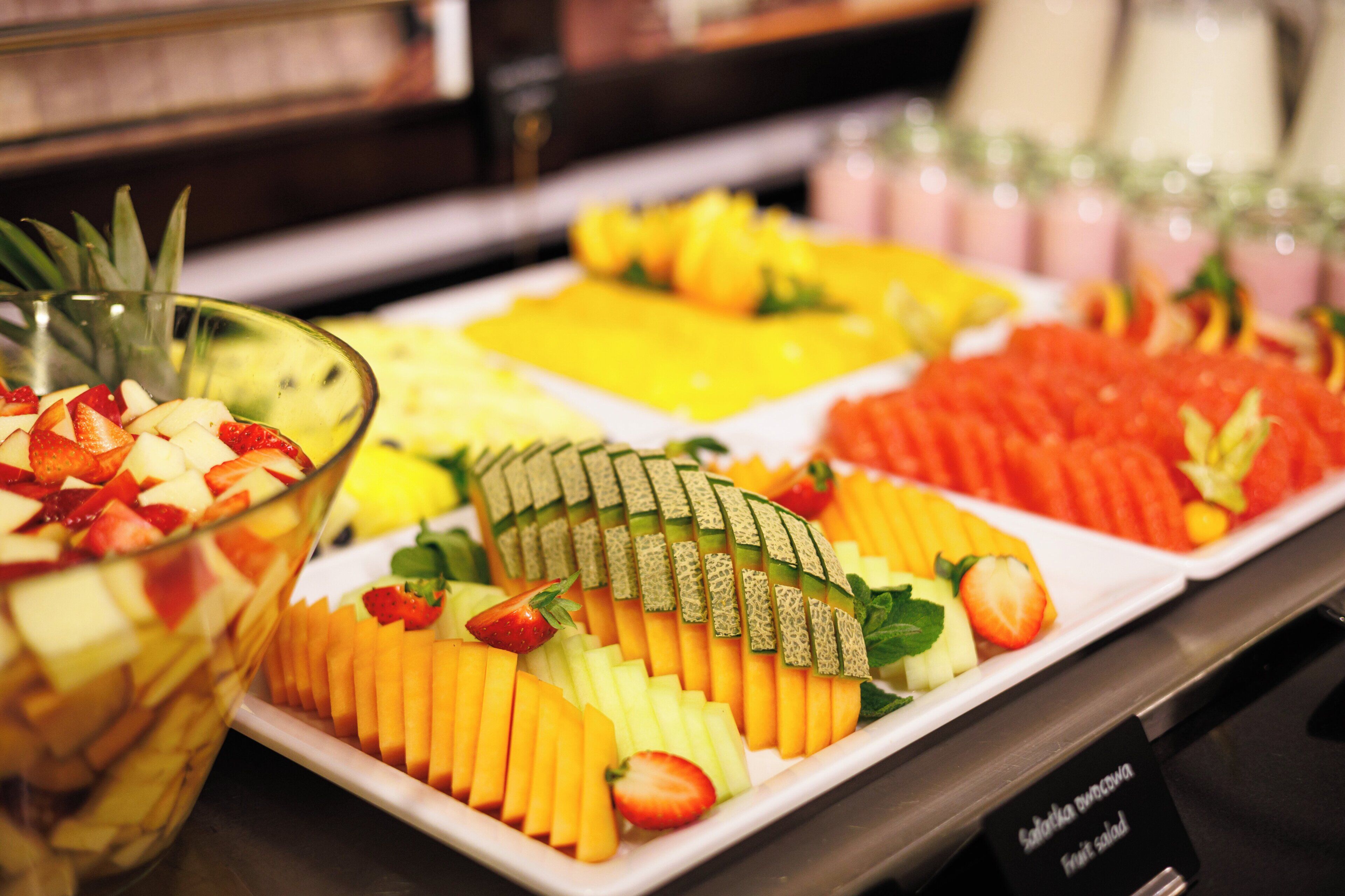 Un bufé con diversas frutas y un tazón de ensalada de frutas.