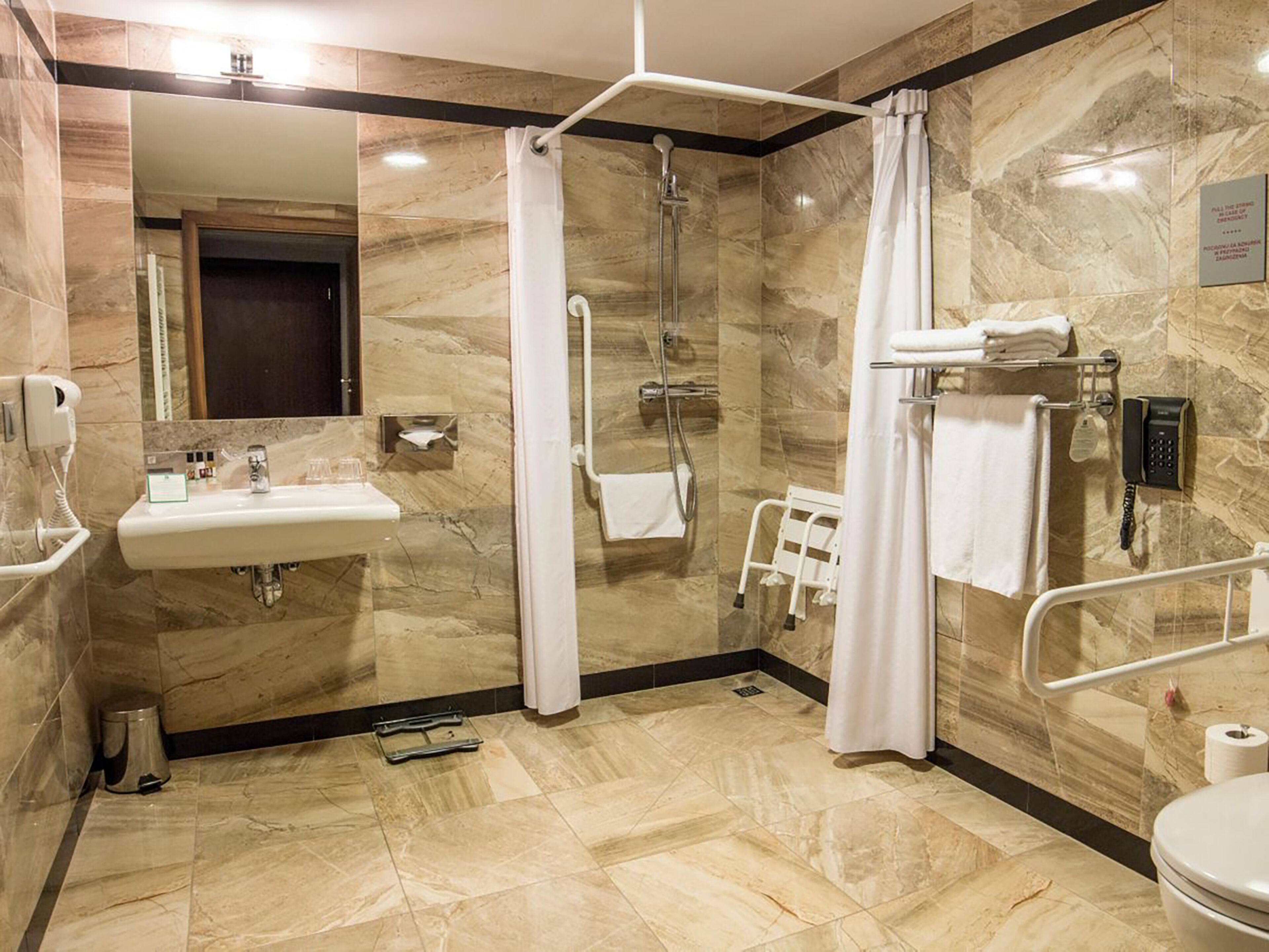 A modern bathroom with a sink, mirror, shower, and toilet.