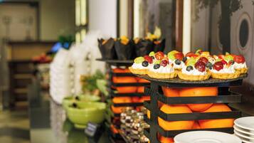 A buffet with fruit-topped desserts and a green bowl in the background.