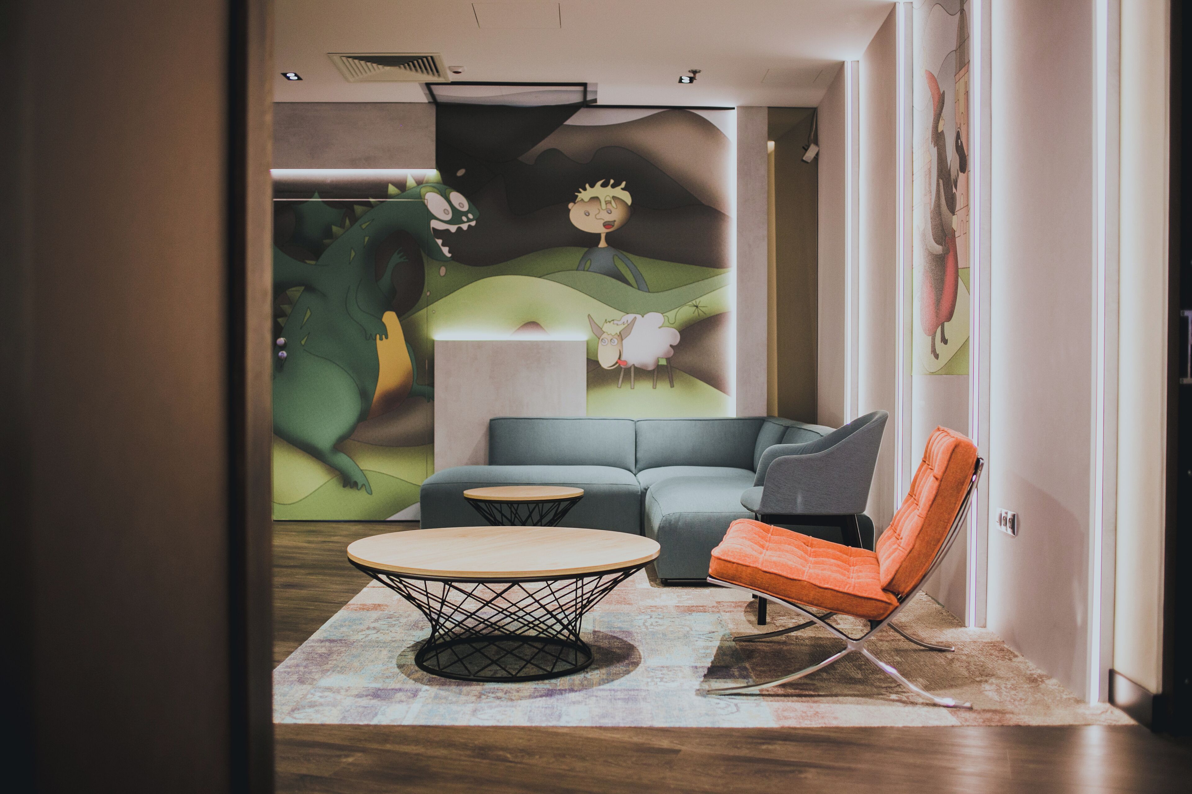 Una sala de estar moderna con un sofá, una mesa de centro redonda y una silla naranja llamativa.