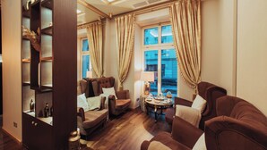 A well-lit living room with a sofa, armchairs, a coffee table, and a bookshelf. - Holiday Inn Krakow City Centre by IHG (Kraków)