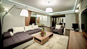 A modern living room with a sectional sofa, a coffee table, and a television. - Holiday Inn Krakow City Centre by IHG (Kraków)