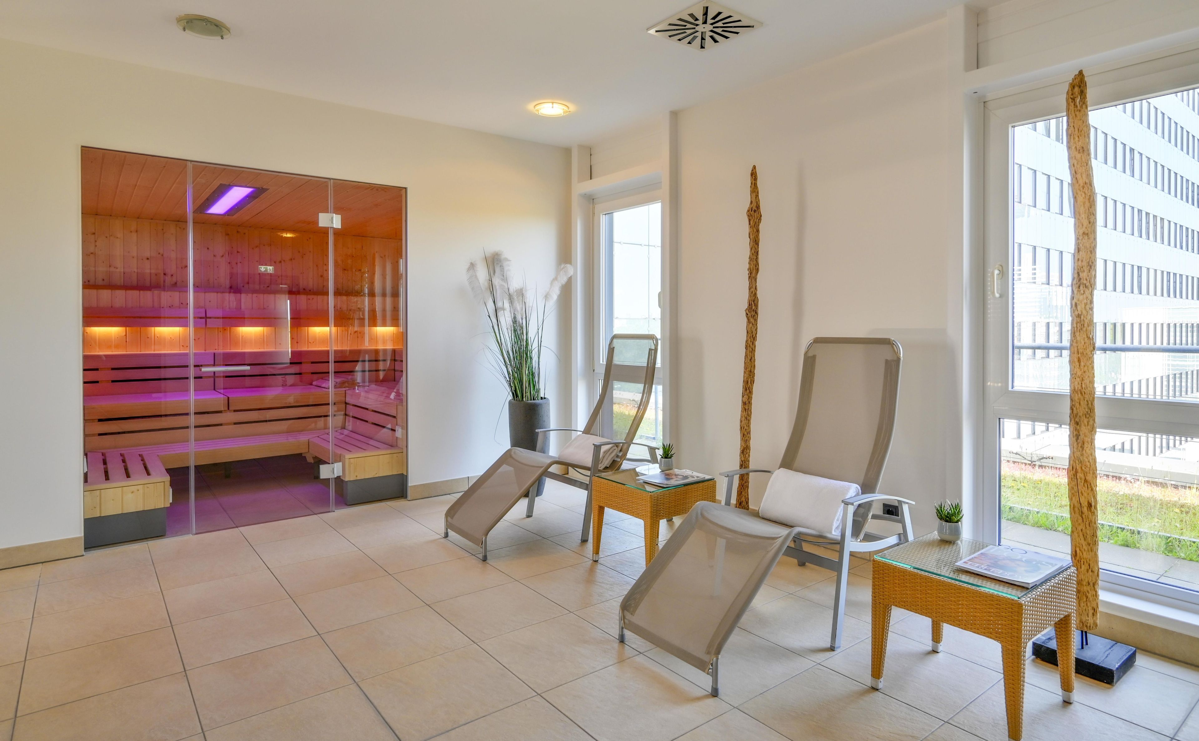 A modern spa room with wooden benches, a glass partition, and a large window offering a view of the outside.
