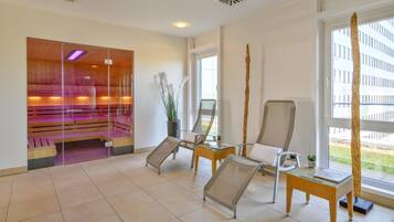 A modern spa room with wooden benches, a glass partition, and a large window offering a view of the outside.