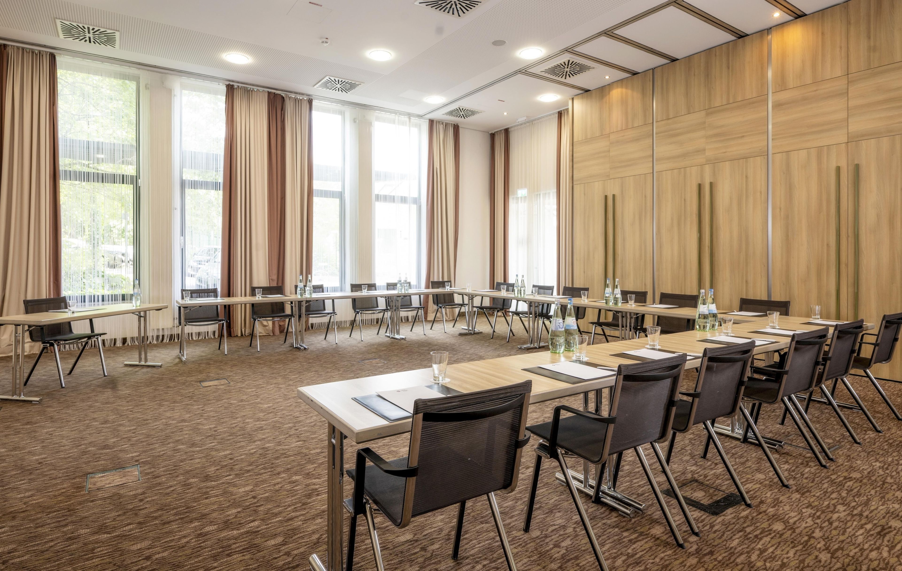 A conference room with long tables, chairs, and a carpeted floor.