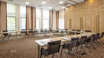 A conference room with long tables, chairs, and a carpeted floor.