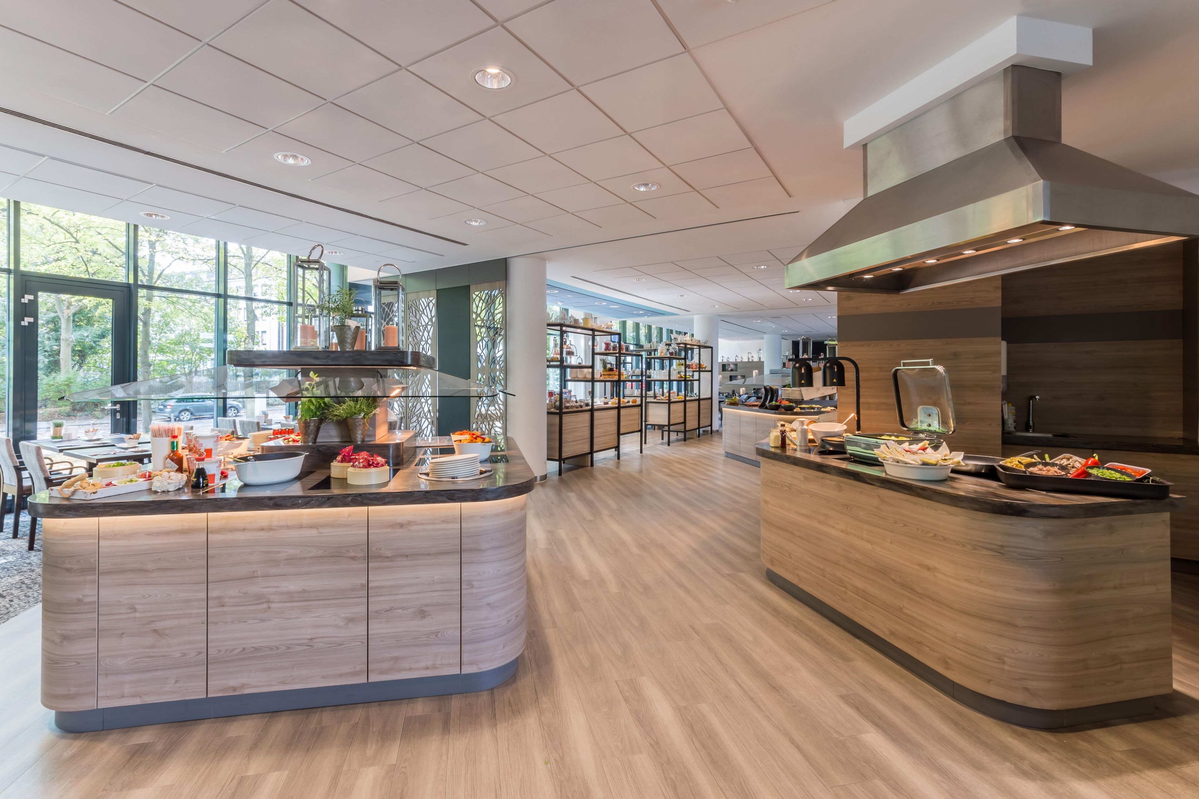 A modern kitchen with a central island, wooden cabinets, and a large window providing natural light.