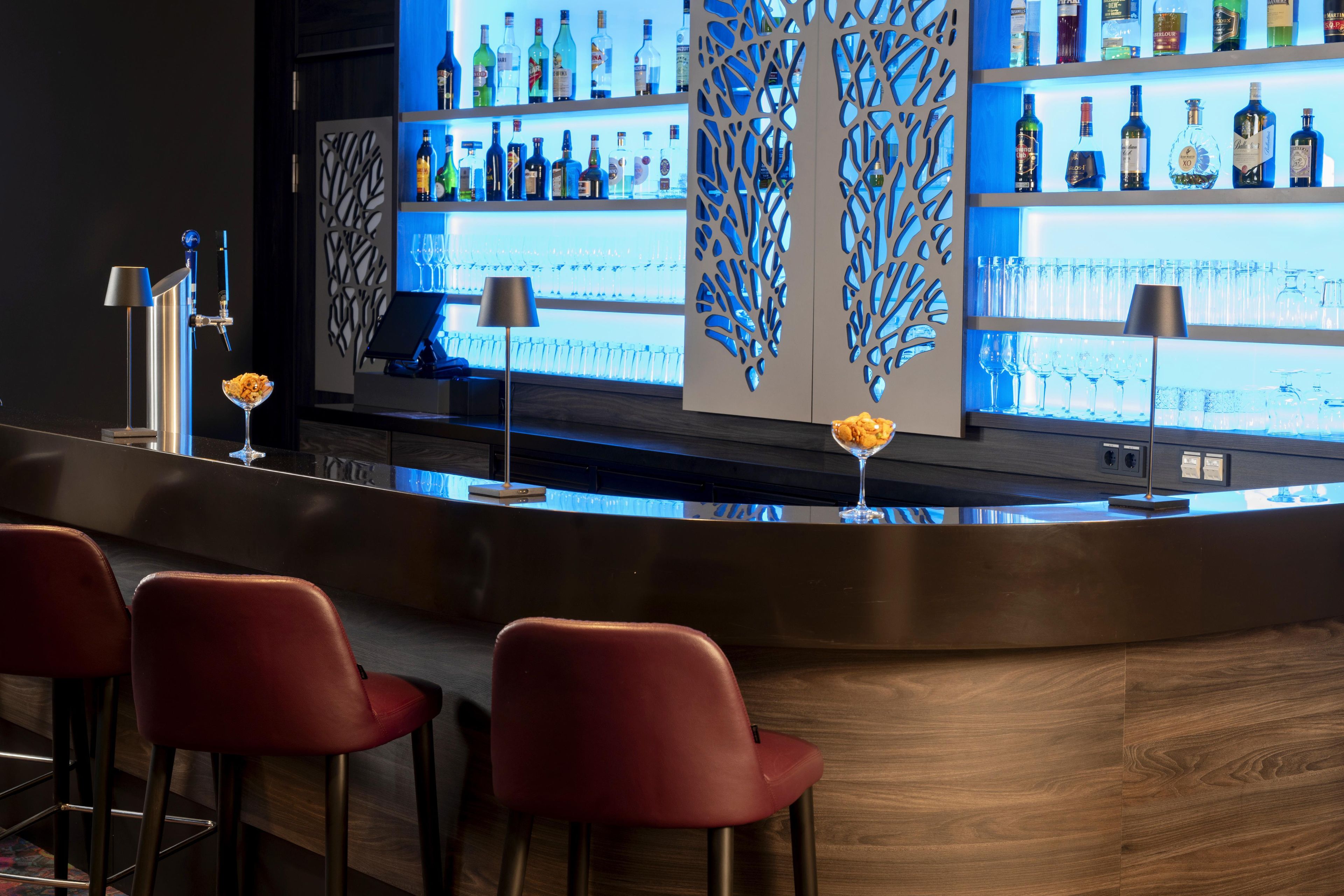 A bar area with a counter, red bar stools, and a decorative wall with a blue pattern.