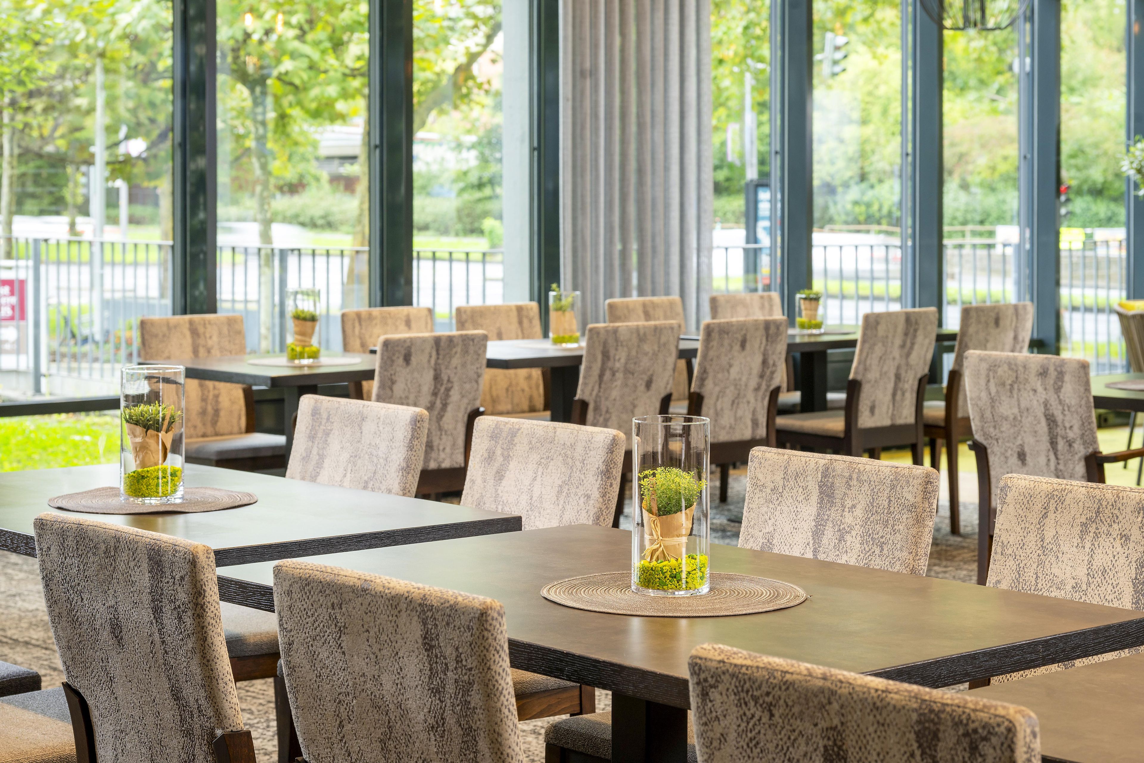 Ein Restaurant mit mehreren Tischen und Stühlen, einige davon mit Blumentöpfen.