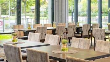 Ein Restaurant mit mehreren Tischen und Stühlen, einige davon mit Blumentöpfen.