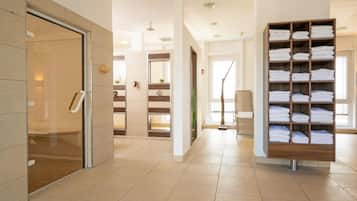 A hotel lobby with a reception desk, a glass door entrance, a wooden towel rack, and a tiled floor.