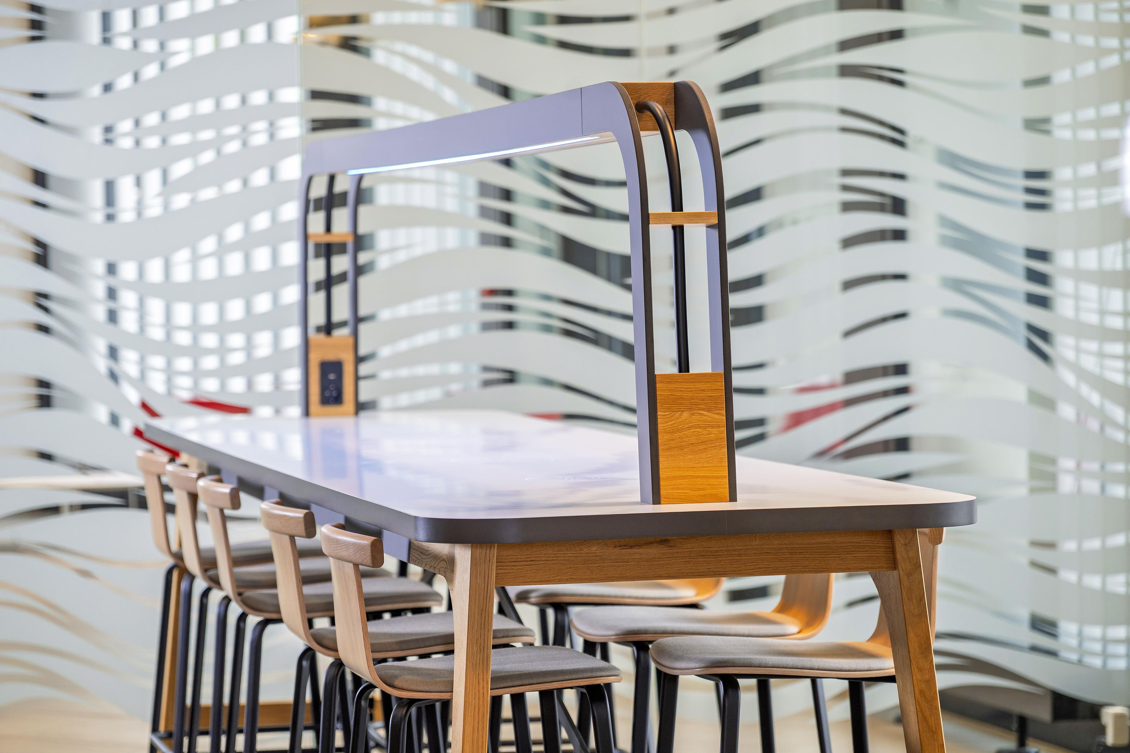 A conference table with chairs, set against a modern, abstract wall design.
