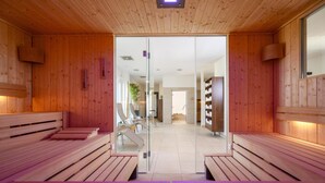 Eine Sauna mit Holzbänken und einer Glastür zu einem Badezimmer.