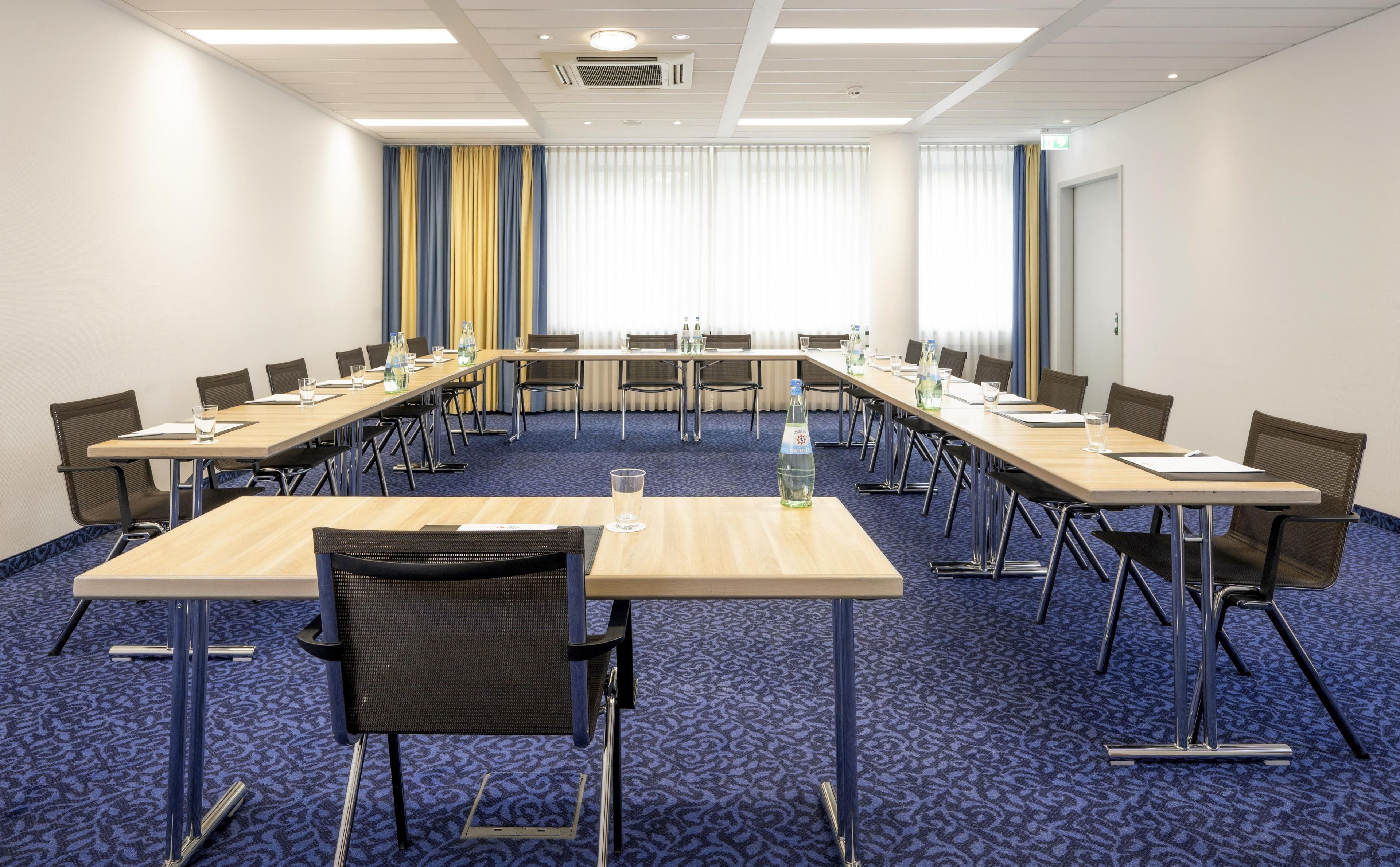 Ein Konferenzraum mit einem langen Tisch, Stühlen und Teppichboden.