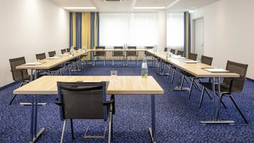 Ein Konferenzraum mit einem langen Tisch, Stühlen und Teppichboden.
