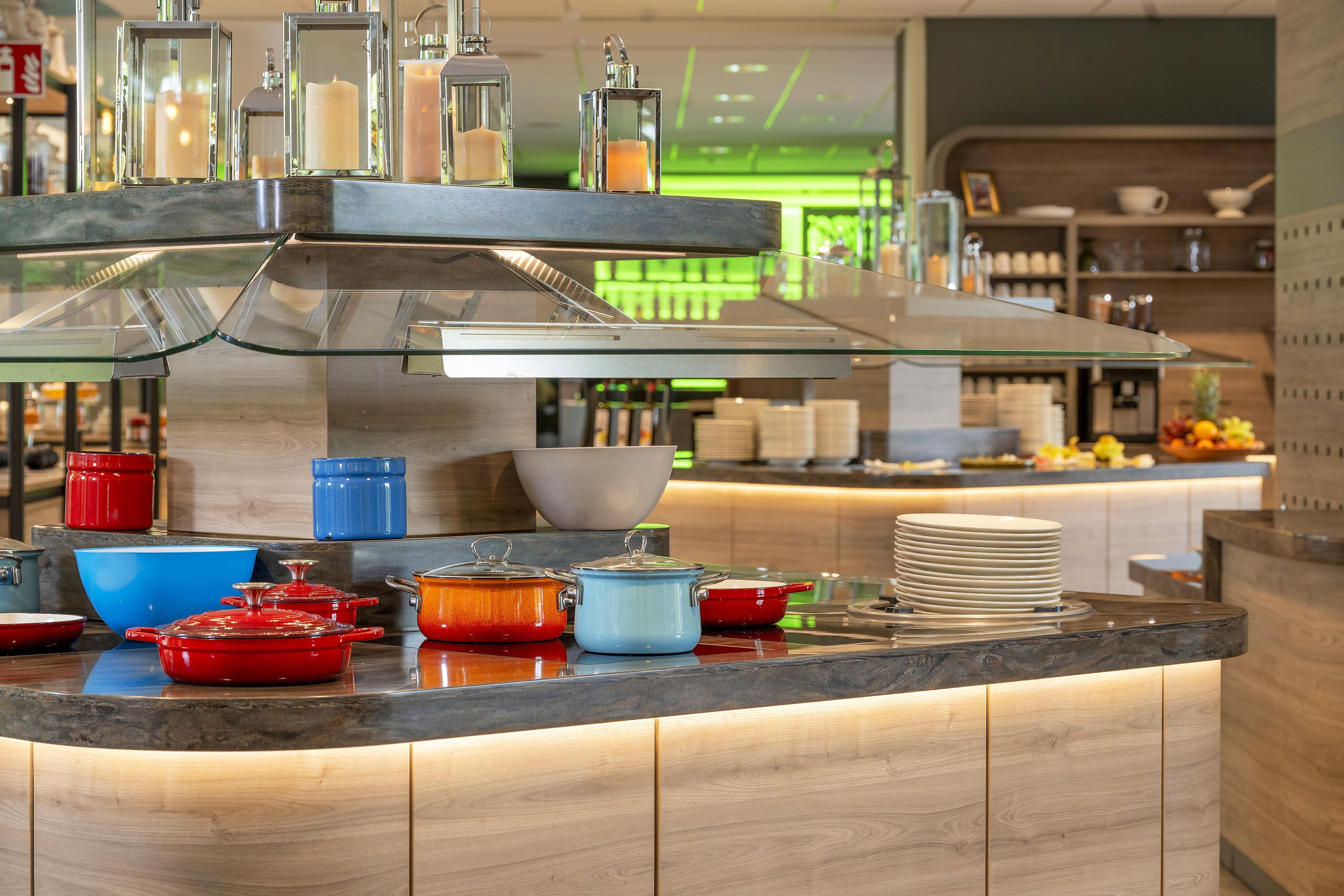 A modern kitchen with a glass-fronted bar area, stainless steel appliances, and colorful cookware.
