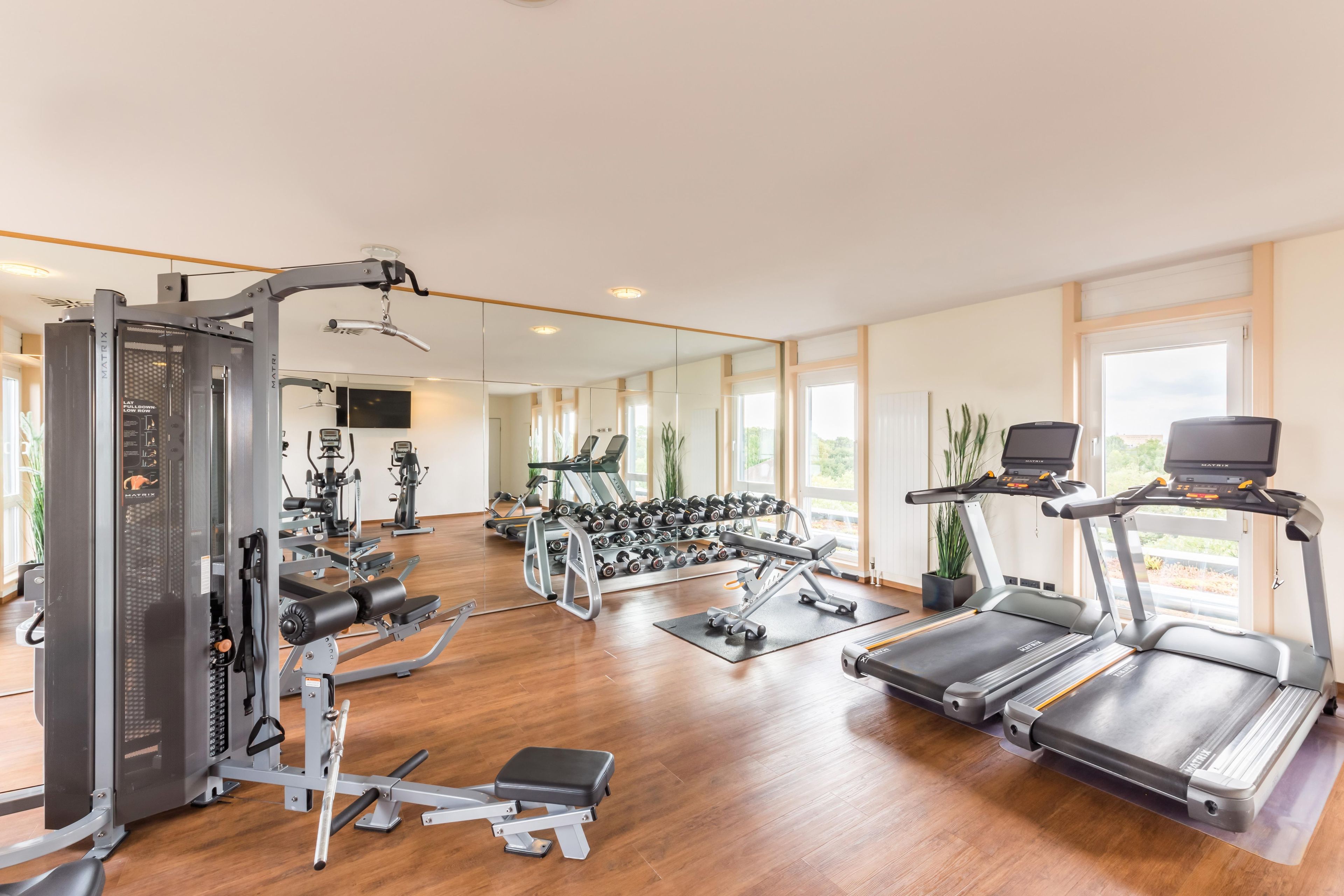 Ein Fitnessstudio mit Laufbändern, Kraftgeräten und Kurzhanteln.