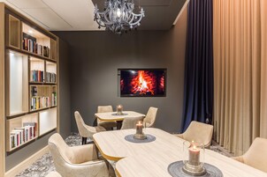 Una habitación de hotel con chimenea, una estantería, una mesa de comedor con sillas y un candelabro.