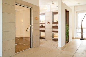 Pasillo de hotel con una puerta de vidrio, un banco de madera y una planta en maceta.