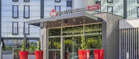 En modern byggnad med en glasfasad och en skylt med texten ”BW Best Western PLUS”.