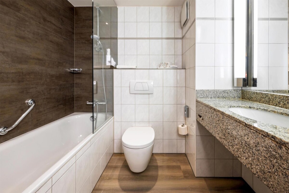Ein modernes Badezimmer mit einer gläsernen Dusche, einer weißen Toilette und einer Arbeitsplatte aus Granit.
