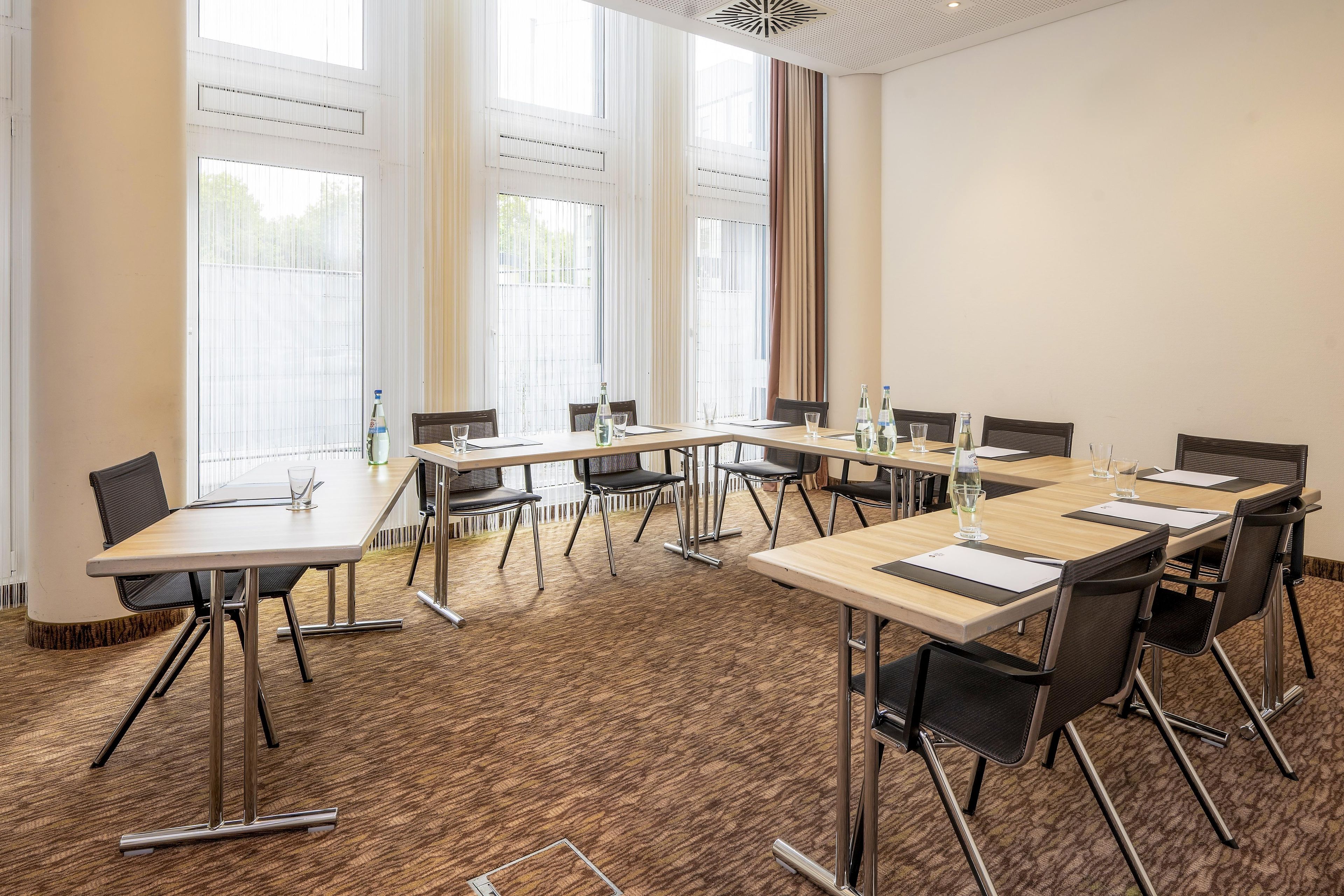 Un salón de conferencias con una larga mesa, sillas y ventanas amplias.