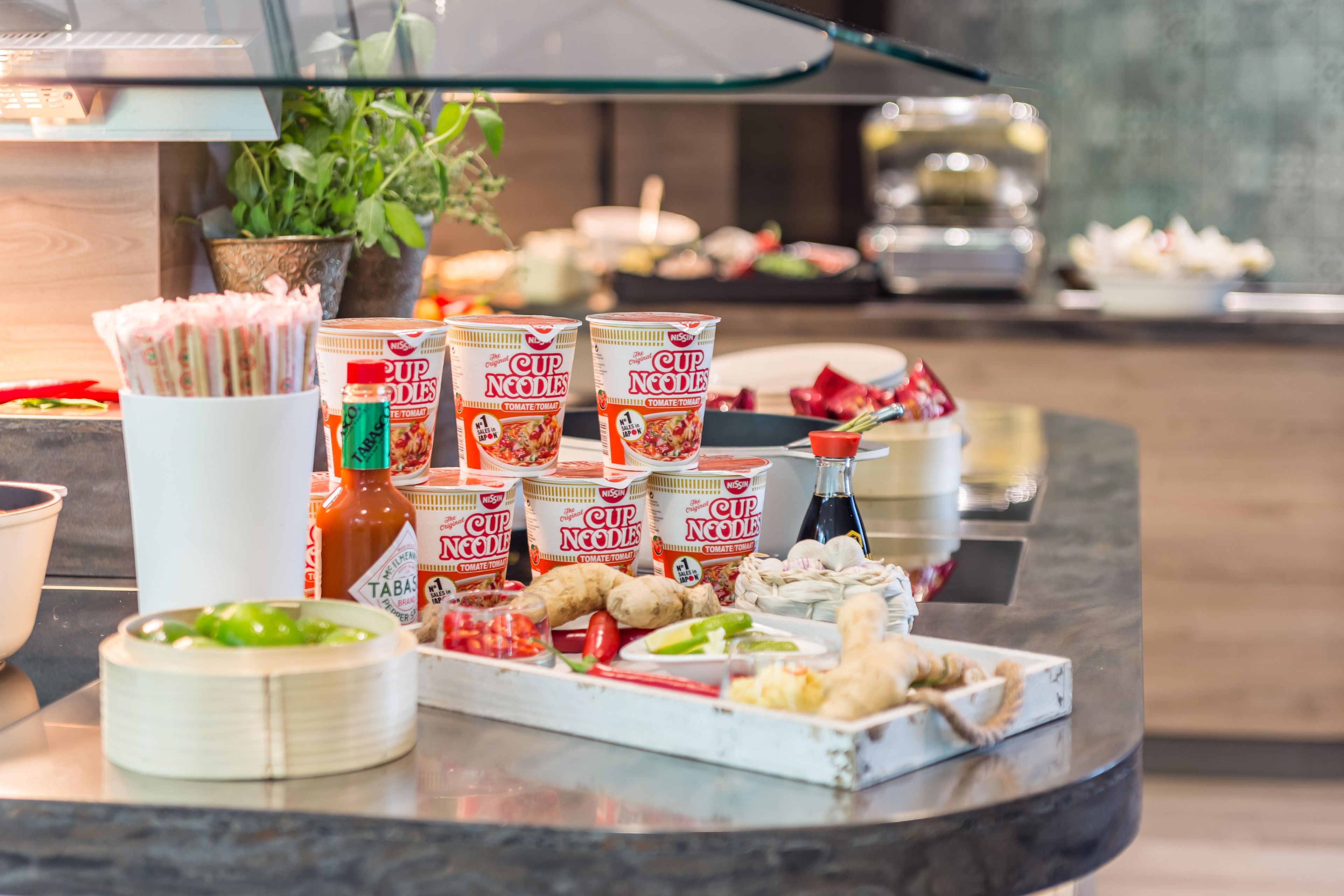 Una mesa de buffet con diferentes alimentos, incluyendo tazones de fideos, salsas y verduras.
