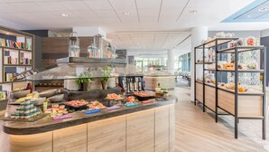 A modern kitchen area with a central island stocked with various food items and condiments. - Best Western Plus Hotel Köln City (Cologne)