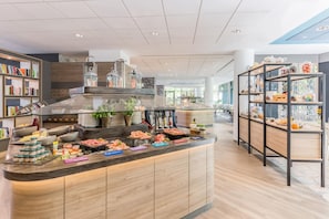 A modern kitchen area with a central island stocked with various food items and condiments. - Best Western Plus Hotel Köln City (Cologne)
