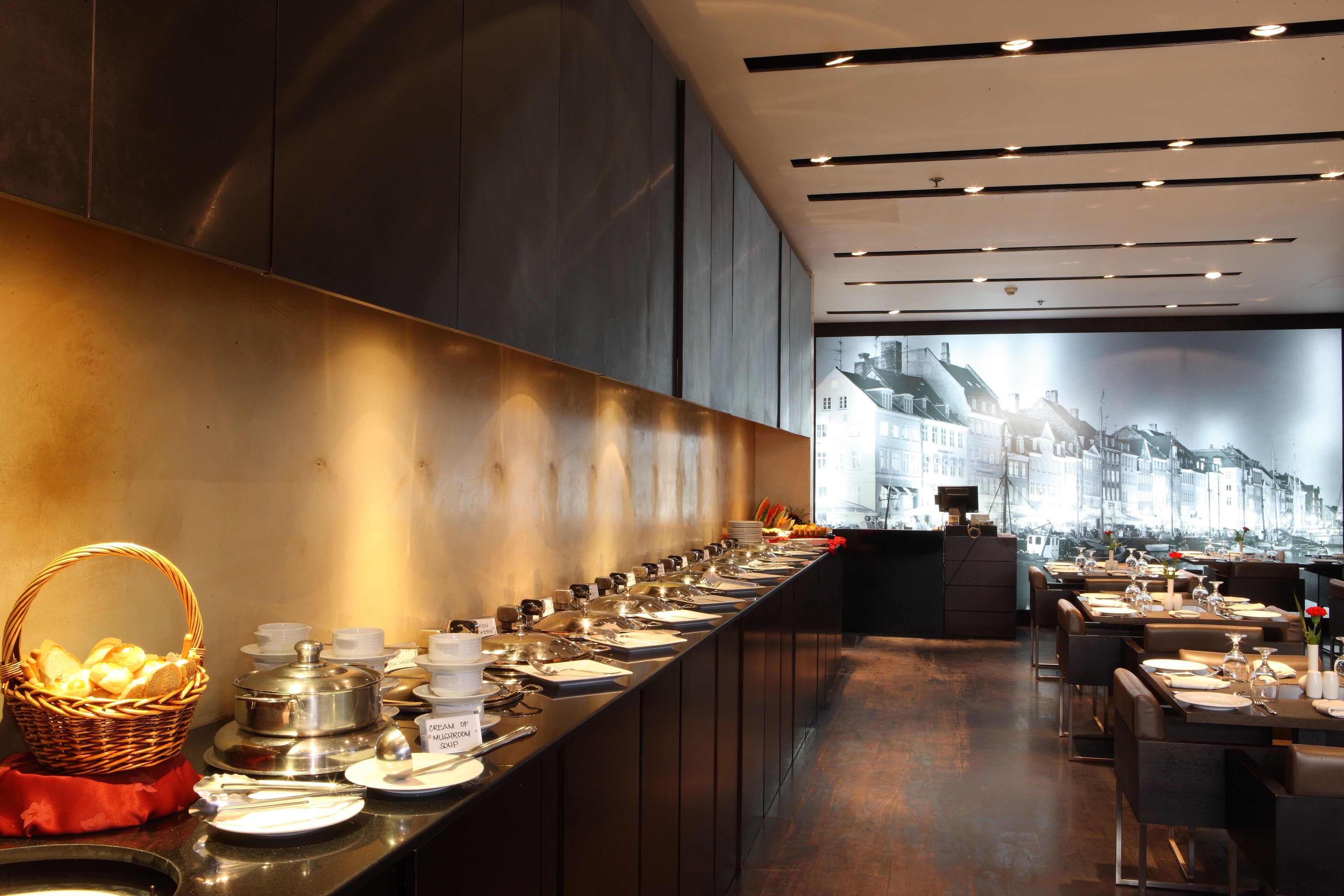 A buffet setup with a variety of dishes and a view of a cityscape through a large window.