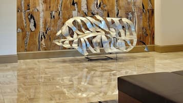 Un interior moderno con un panel de pared de madera, una escultura metálica y un tapete a rayas.